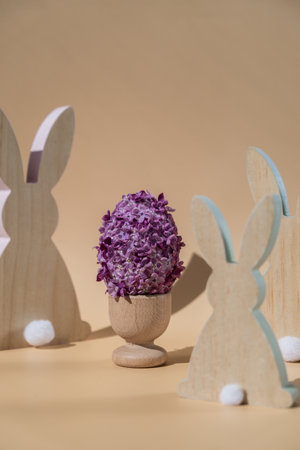 Creative Easter egg shape made of lilac spring petals flowers. Eco-friendly wooden bunnies...