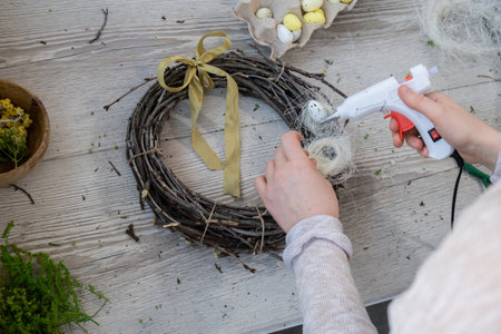 DIY process of woman making candid Easter wreath arrangement decor. Small business, self employed entrepreneur, self-made career. Series of handmade craft instruction. Zero waste eco-friendly springtimeの写真素材