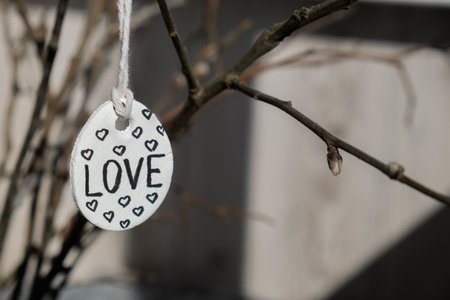 Clay Easter eggs with words RISEN HOPE BELIEVE PEACE LOVE WONDER on wooden twig. Children air dry clay activity handicraft idea. Preparing for Easter holiday decorating. Modern organic design minimalistic plastic free sustainableの写真素材
