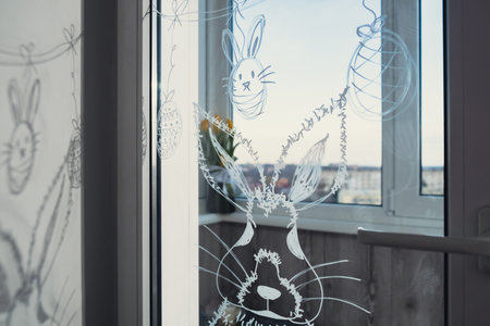 Zero cost responsible holiday decor economically driven. Painted Easter bunny rabbit on window glass indoor at home. Affordable alternative Easter springtime seasonal tradition ideas decorationの写真素材