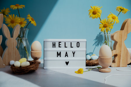 Lightbox with message HELLO MAY on festive blue background and eco-friendly zero waste natural decoration. Yellow daisies flowers. Bunny egg. Holiday greetingの写真素材