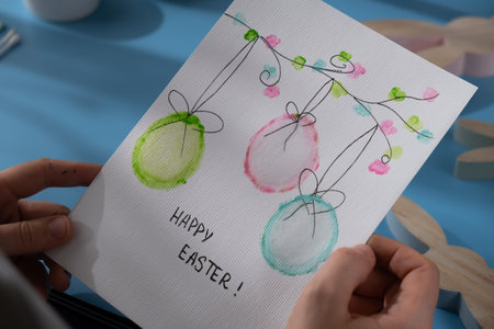 Person holding handmade greeting card with message HAPPY EASTER written in beautiful handwriting. Gesture shows excitement and joy for the upcoming event. Springtime holiday gift present zero cost ideas. Creative artの写真素材