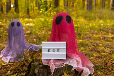 Halloween holiday concept. Handmade colorful ghosts made from bandages and glue in autumn forest background. Childrens art project. DIYの写真素材