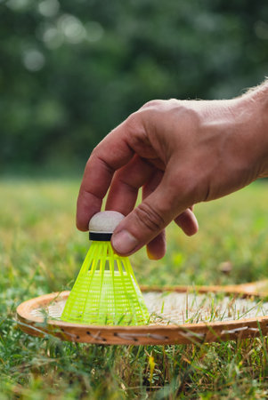Neon yellow badminton shuttlecock and racket on green grass outdoors. Copy space soft selective focus on shuttlecocks.の写真素材