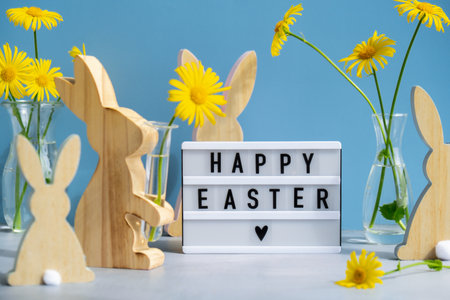 Happy Easter text on Lightbox with bunny wooden figures and fresh flowers. Easter composition content still life. Christian symbolsの写真素材