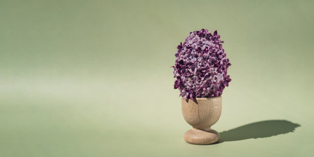 Easter egg made of lilac spring flowers in pastel green background. Sustainable holiday minimalistic still life composition. Copy space template for invitation greeting cardの写真素材