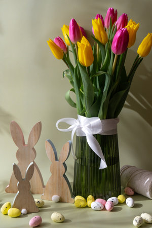 Happy EASTER composition wooden bunny eggs Bouquet of colorful tulips in vase in pastel green background. Copy space for greeting card. Holiday flowers springtimeの写真素材