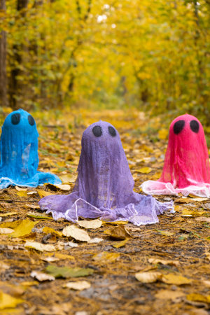 Trick or treat halloween colorful ghosts made of bandages in fall autumnal forest. Halloween greeting card. Handicraft handmade diyの写真素材