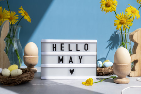 Traditional greeting to christian holiday. Festive mood composition with bunnies and yellow flowers on pastel blue background. Sustainable natural materialsの写真素材
