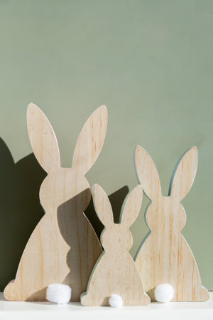 Minimalistic creative Easter concept. Two Easter bunnies under symbolic roof on green background. Celebration Easter holiday at home with family. Poster or greeting cardの写真素材