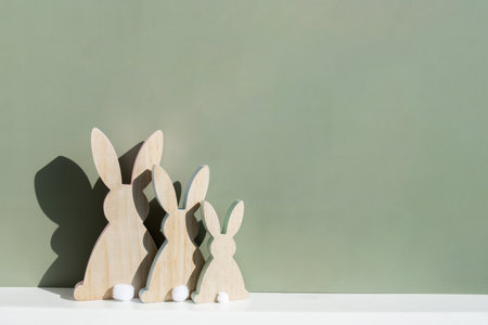 Minimalistic creative Easter concept. Two Easter bunnies under symbolic roof on green background....