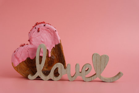 Wooden word LOVE symbol Delicious fresh croissant topped with colorful flavor Ganache. Creation...