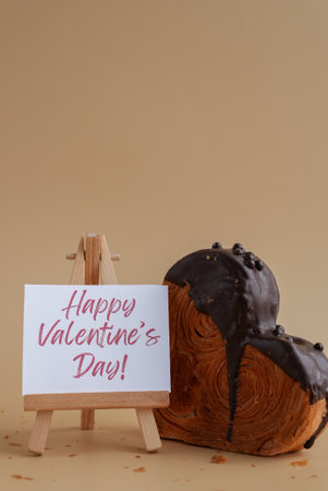 Happy Valentines Day saying caption on greeting card Delightful heartshaped pastry croissant treat, beautifully topped with colorful frosting galore. Copy space. Food experimentation viral dessert creative baking trendの写真素材
