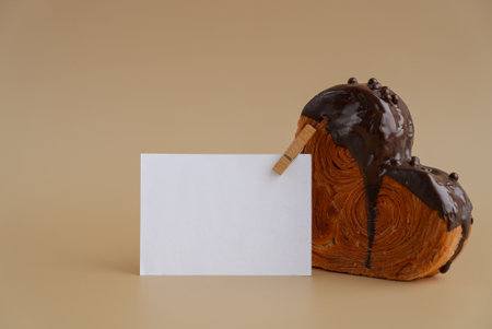 Empty paper note template sample mock up blank for wishes greeting holiday card Heartshaped pastry croissant treat topped with colorful frosting. Food experimentation dessert baking trendの写真素材