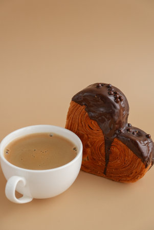 Coffee latte cappuccino drink beverage morning breakfast Heart shaped dark chocolate croissant on beige background with copy space. Puff pastry new trendy sweet dessert bakery. Creamy doughの写真素材