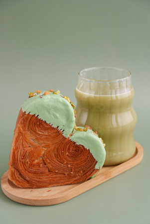 Green tea Matcha latte cappuccino beverage Morning breakfast gift idea Heart shaped pistachio croissant on green background with copy space. Puff pastry trendy sweet dessert bakery. Creamy dough experimentの写真素材