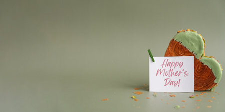 HAPPY MOTHERS DAY greeting card Heart shaped pistachio croissant on green background with copy space. Puff pastry trendy sweet dessert bakery. Creamy dough experimentの写真素材