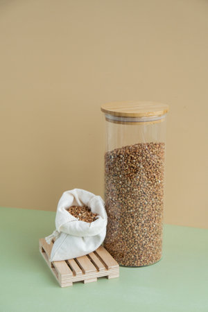 Refillable glass jar with raw buckwheat porridge and cotton bag. Copy space Refill product format eco-friendly living. Filling reusable container Whole spelt grain species. High protein fiber-rich vegan plant based food ingredient. Gluten free superfood healthy nutritional dietaryの写真素材