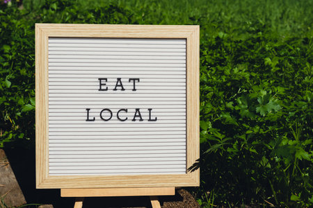 EAT LOCAL message on background of fresh eco-friendly bio grown green herb parsley in garden. Countryside food production concept. Locally produce harvesting. Sustainabilityの写真素材