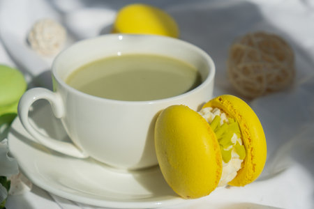 Sweet yellow macaron dessert Cup of green plant based matcha tea latte in cozy morning bed atmosphere. Creative holiday romantic date idea.の写真素材