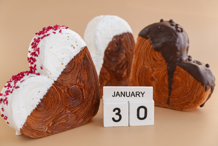 30 January National Croissant Day holiday calendar date celebration greeting card Heart shaped dark chocolate flavor croissant on beige background with copy space. Puff pastry new trendy sweet dessert bakery. Creamy doughの写真素材