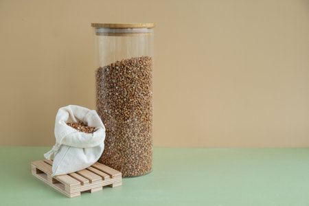 Refillable glass jar with raw buckwheat porridge and cotton bag. Copy space Refill product format eco-friendly living. Filling reusable container Whole spelt grain species. High protein fiber-rich vegan plant based food ingredient. Gluten free superfood healthy nutritional dietaryの写真素材