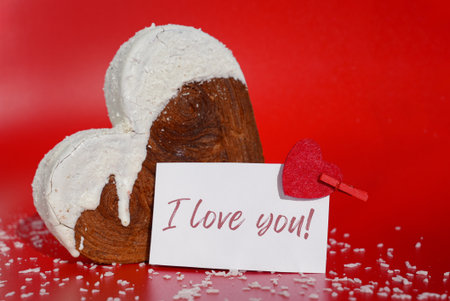 I LOVE YOU saying on paper holiday card Valentine's day celebration Heart shaped coconut flavor croissant on red background with copy space. Puff pastry new trendy sweet dessert bakery. Creamy dough experimentの写真素材