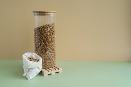 Refillable glass jar with raw buckwheat porridge and cotton bag. Copy space Refill product format eco-friendly living. Filling reusable container Whole spelt grain species. High protein fiber-rich vegan plant based food ingredient. Gluten free superfood healthy nutritional dietaryの写真素材