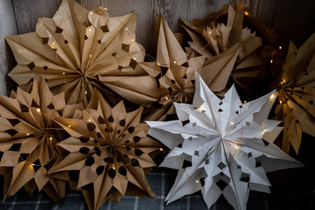 3d craft snowflakes with garland lights. Sustainableminded Christmas cozy home handmade decoration. Tutorial for making do it yourself craft paper lunch bags and hot glue. Seasonal activity for kids. 3D snowflakes eve preparationの写真素材