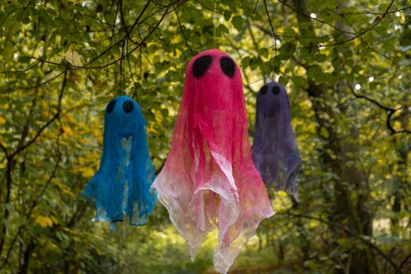 Creative handmade Halloween holiday decoration. Colorful ghost flying in autumn leaves forest. Zero waste homemade decor. Mystic placeの写真素材