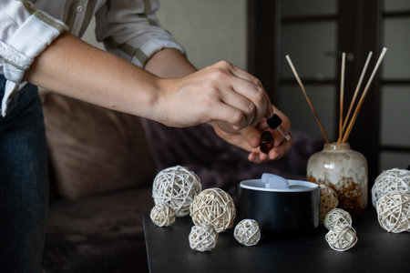 Unrecognizable woman adding essential oil to Home fragrance aromatic diffuser with essential oil....