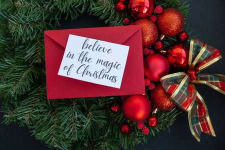 Greeting card with BELIEVE IN THE MAGIC OF CHRISTMAS text on handmade Christmas wreath. Festive mood new year celebration. Postcard decoration decorの写真素材