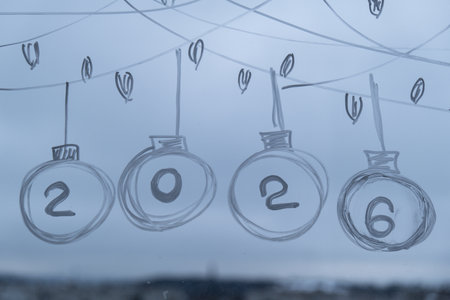 Sustainable responsible holiday decor. New Year number 2026 painted on window glass indoor at home....