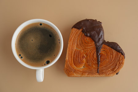 Coffee latte cappuccino drink beverage morning breakfast Heart shaped dark chocolate croissant on beige background with copy space. Puff pastry new trendy sweet dessert bakery. Creamy doughの写真素材