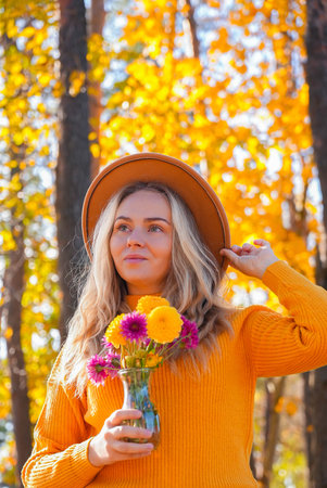 Woman with yellow dahlia Autumn garden colorful flowers. Beautiful autumnal bouquet dahlia chrysanthemum. Red pink orange fall color fall floral background. Flower shop and florist design conceptの写真素材