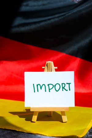 Paper note with words IMPORT on National symbol of Germany. German wave silky flag background. Economy industry global market international shippingの写真素材