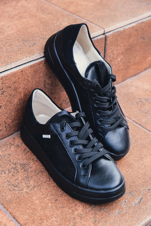 Elegant black leather womens shoes blank product for branding displayed. New casual female sneakers no-brand footwear e-commerce. No logo productの写真素材