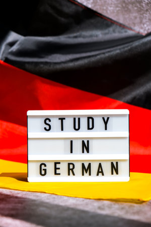 Lightbox with text STUDY IN GERMAN National symbol of Germany. German wave silky flag background. Education and learningの写真素材