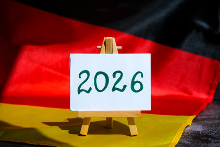 Paper note with text 2026 on National symbol of Germany. German wave silky flag background.