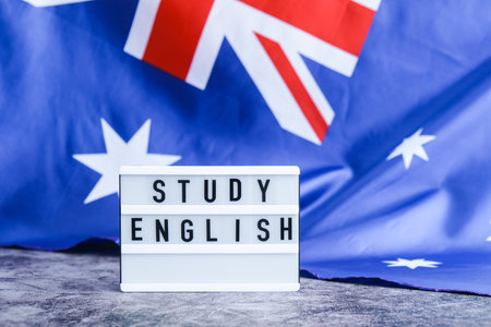 Message STUDY ENGLISH on background of Australian flag made from silk. Australia national flag with concept of tourism and traveling students opportunities scholarship programsの写真素材