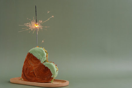 Festive holiday candle sparkler birthday anniversary celebration Heart shaped pistachio croissant on...
