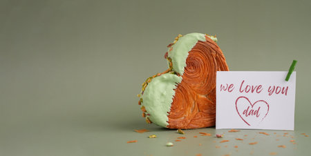 Heart shaped pistachio croissant on green background with copy space. Puff pastry trendy sweet...