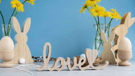 Wooden word LOVE with bunny figures eggs and fresh flowers. Easter composition content still life....
