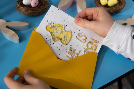 Person holding handmade greeting card with message HE IS RISEN written in beautiful handwriting. Gesture shows excitement and joy for the upcoming event. Springtime holiday gift present zero cost ideas. Creative artの写真素材
