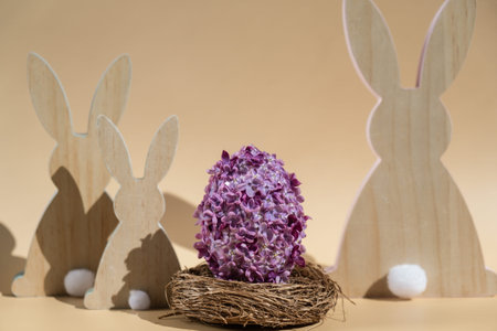 Creative Easter egg shape made of lilac spring petals flowers. Eco-friendly wooden bunnies...