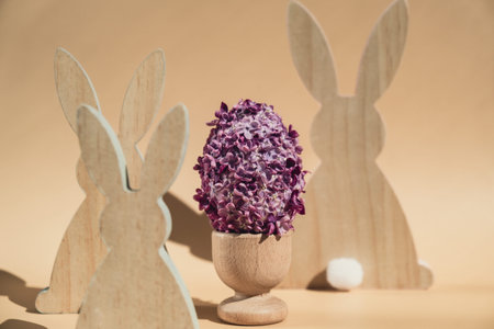 Creative Easter egg shape made of lilac spring petals flowers. Eco-friendly wooden bunnies...