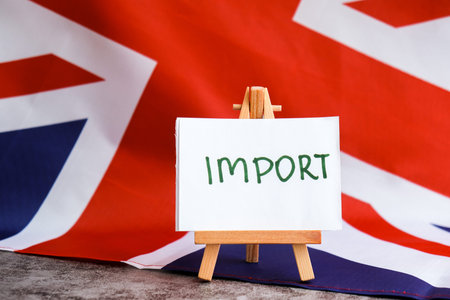 Paper note with words IMPORT on National symbol of Great Britain. British wave the UK silky flag...