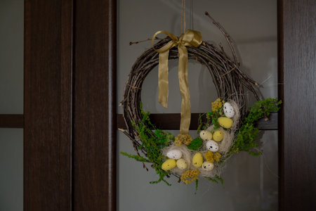 Handmade Easter wreath festive yellow egg decorations on front door. Traditional holiday preparation...