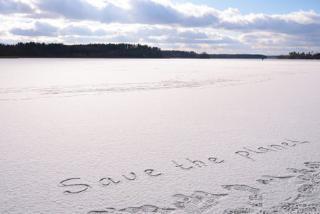 Written SAVE THE PLANET on snow background message ice outdoor on ground in winter. Writing text...