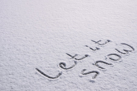 Written LET IT SNOW on snow background message ice outdoor on ground in winter. Writing text sign and drawing on field in frozen background. Weather is changing cold season has arrived. Mockup Copy space Creative art and textureの写真素材
